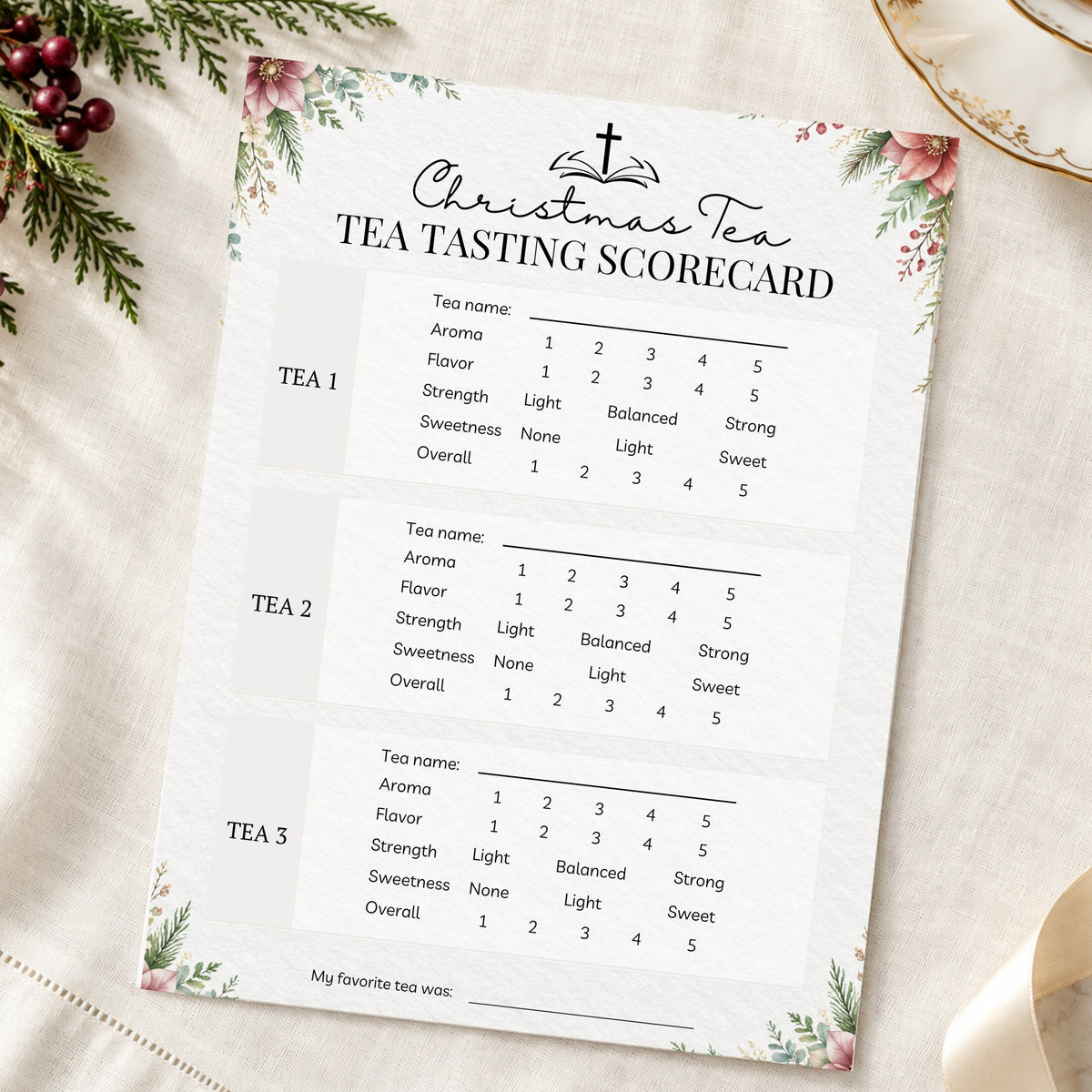 A printed Christmas-themed tea tasting scorecard laid on a soft cream fabric background with floral corner decorations and greenery. The card has black text and three labeled tea tasting sections with rating scales.