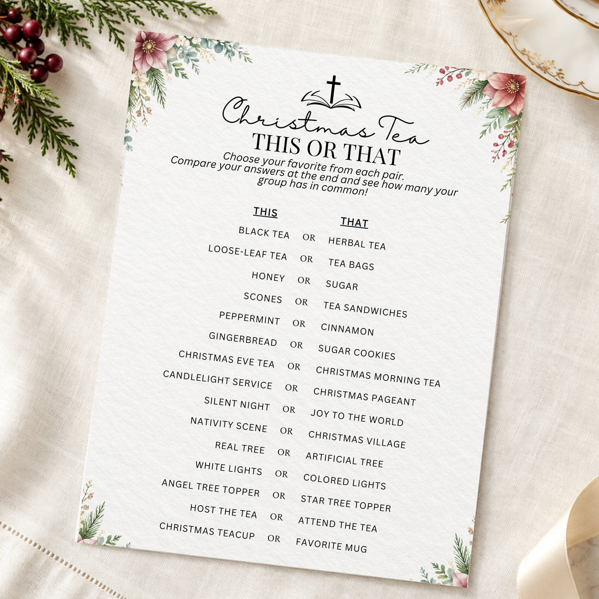 A printed Christmas tea game card titled 'Christmas Tea THIS OR THAT' with a list of tea and holiday pairing options, styled on a cream fabric background with floral greenery and ribbon.